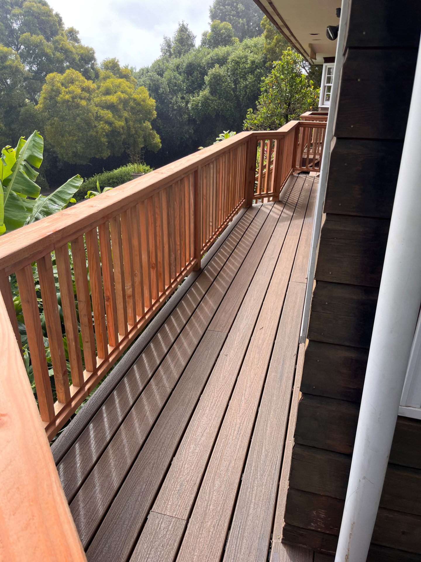 New hardwood deck walkway with a redwood railing alongside a Waimea home